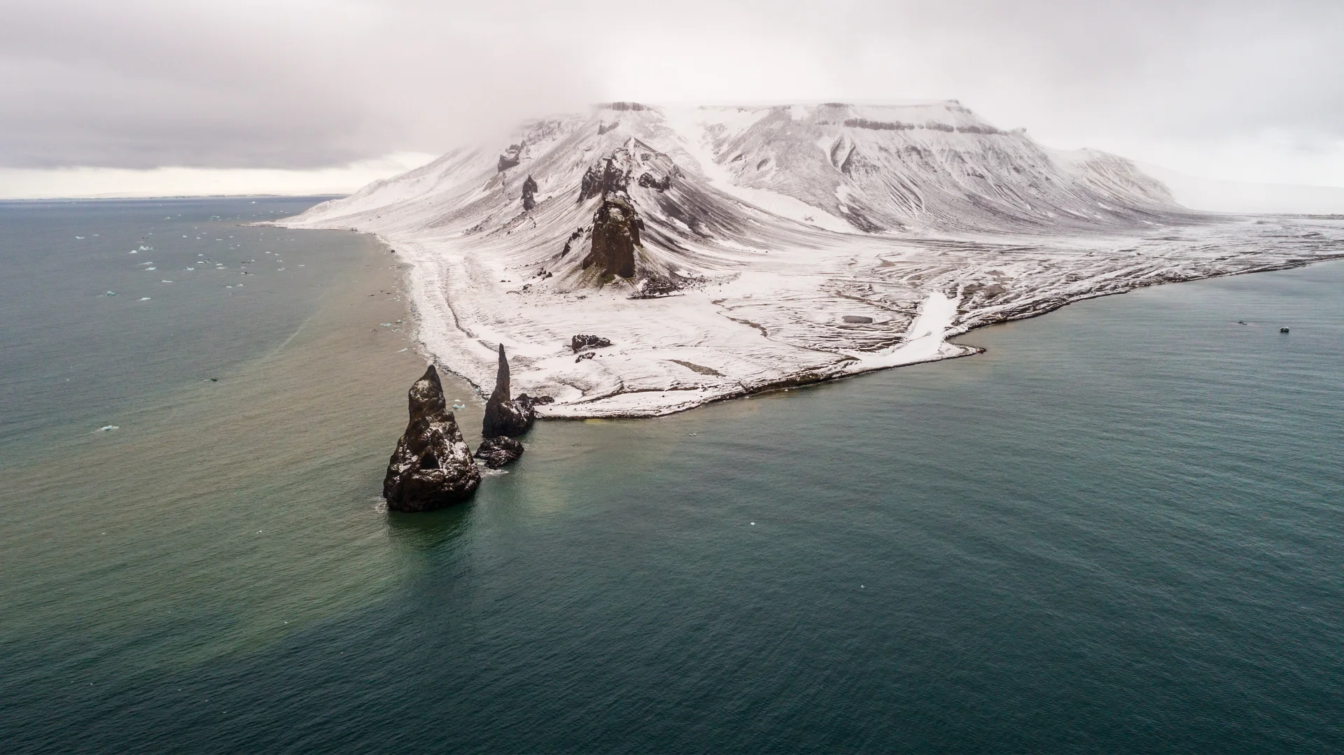 Snow-covered headlands and dark rock spires at Cape Tegetthoff on Hall Island.